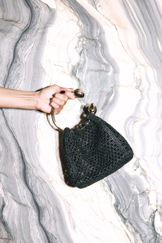 The Black Quinta Bag held against marble